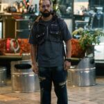 Portrait of a man in street style clothing outside a Tehran barbershop.